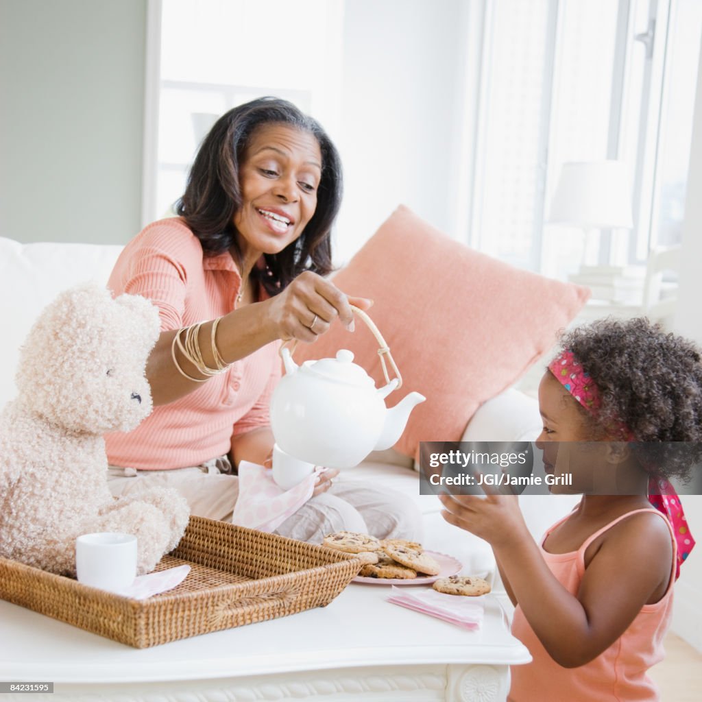African grandmother having tea party with granddaughter
