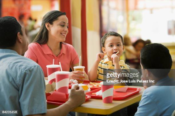 hispanic family eating in fast food restaurant - fast food french fries stock pictures, royalty-free photos & images