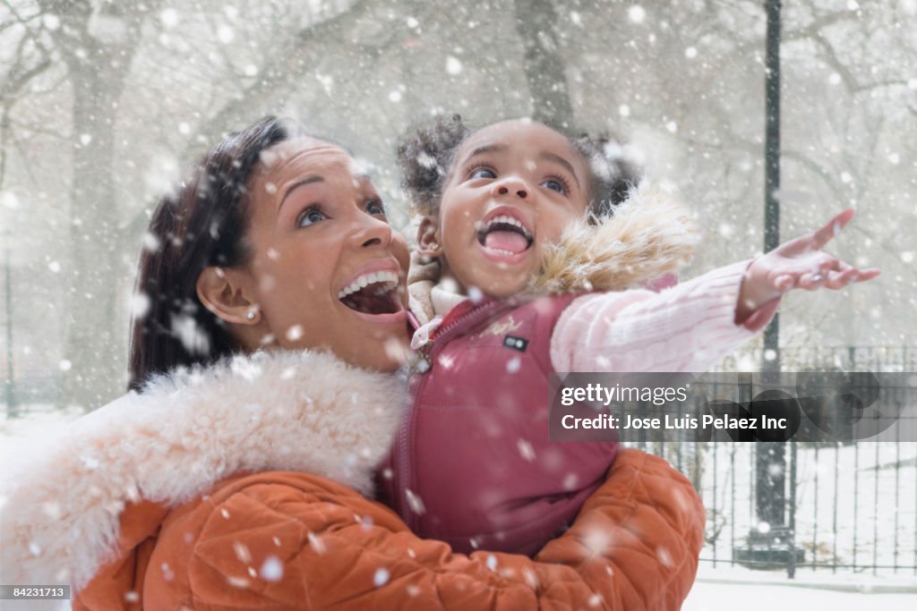 African mother holding daughter in falling snow