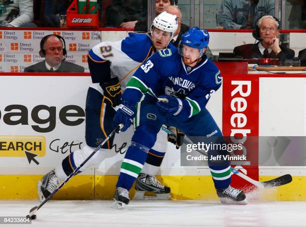 Henrik Sedin of the Vancouver Canucks keeps the puck away from a check by Patrik Berglund of the St. Louis Blues during their game at General Motors...