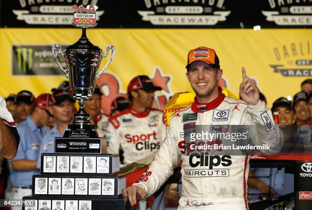 Denny Hamlin, driver of the Sport Clips Toyota, poses with the trophy in Victory Lane after winning the Monster Energy NASCAR Cup Series Bojangles'...