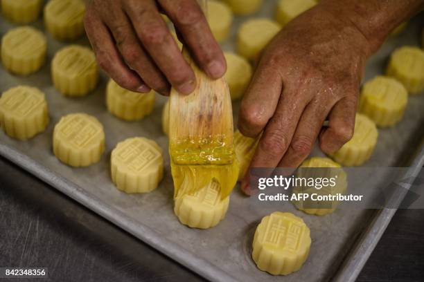 In this photo taken on August 21 chef Yip Wing-wah brushes fresh egg yolk on his pre-baked signature "spring moon mini egg custard mooncakes" at Hong...