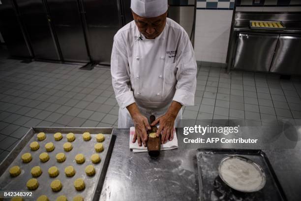In this photo taken on August 21 chef Yip Wing-wah uses a heavy wooden holder containing a dough ball, which he bangs three times on a worktop to pop...