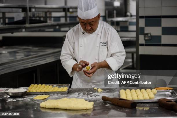 In this photo taken on August 21 chef Yip Wing-wah uses dough to wrap the filling of his signature "spring moon mini egg custard mooncakes" at Hong...