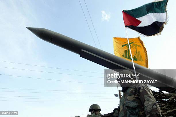 Lebanese Shiite Hezbollah militants parade with a missile as the Palestinian and the movement's flags flutter during an annual parade in the southern...