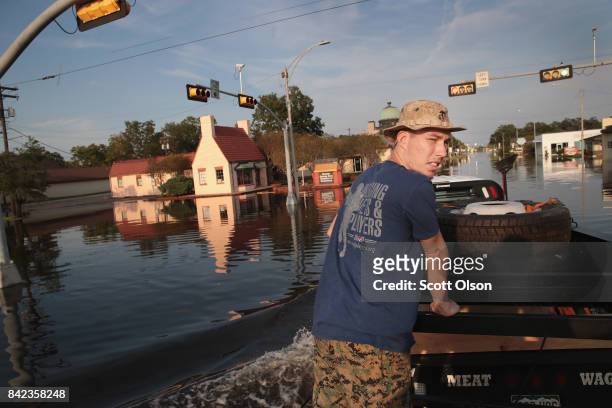 Chris Rogers, a volunteer with Merging Vets and Players, helps to distribute food and water to flood victims after the town was inundated when...