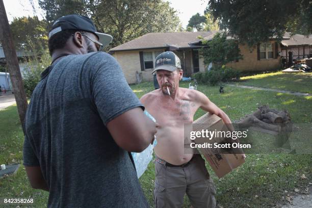 Former NFL player Oren O'Neal and a volunteer with Merging Vets and Players, distributes food and water to a flood victim after the town was...