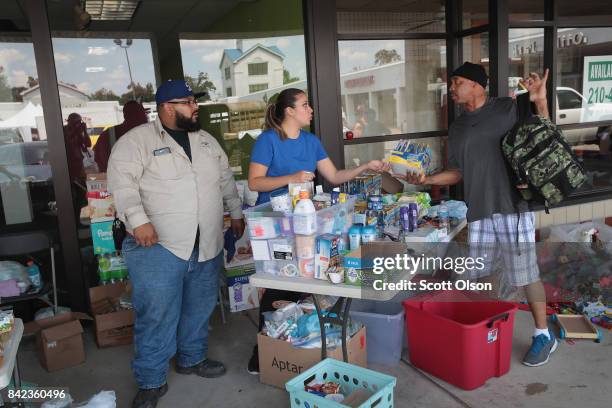 Volunteers Jesse Puga and Marisol Zabala help to distribute relief supplies to flood victims after torrential rains pounded Southeast Texas following...