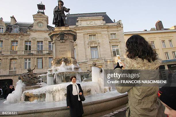 Woman poses for a picture in front of a frozen fountain taken on January 10, 2009 in Reims, eastern France. Bad weather in France forced school...