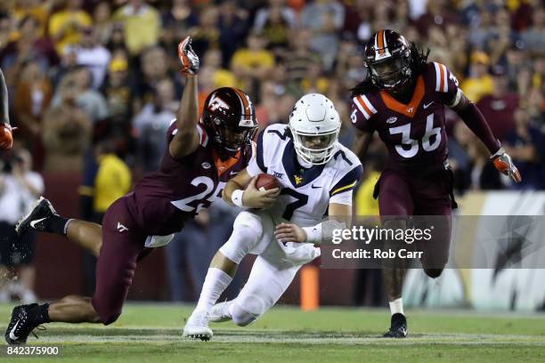 Auarterback Will Grier of the West Virginia Mountaineers is tackled by Adonis Alexander and Anthony Shegog of the Virginia Tech Hokies at FedExField...