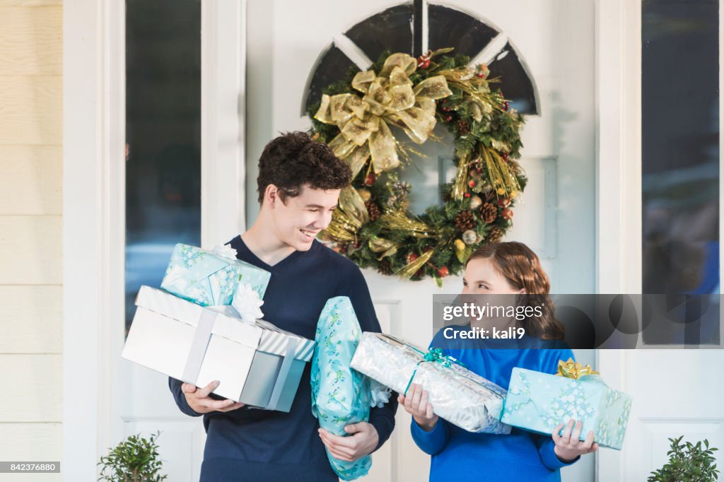 Teenage boy and sister carrying Christmas gifts