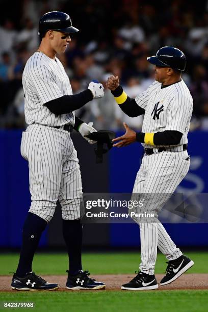 Aaron Judge fist bumps first base coach Tony Peña both of the New York Yankees near second base after a double against the Boston Red Sox during the...