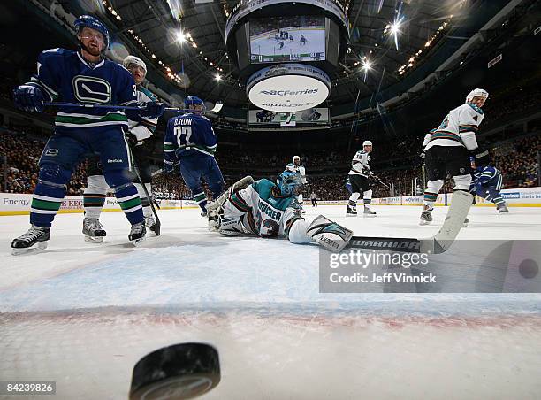 Henrik Sedin of the Vancouver Canucks and teammate Daniel Sedin look on as teammate Mats Sundin scores his first goal as a Canuck on Brian Boucher of...