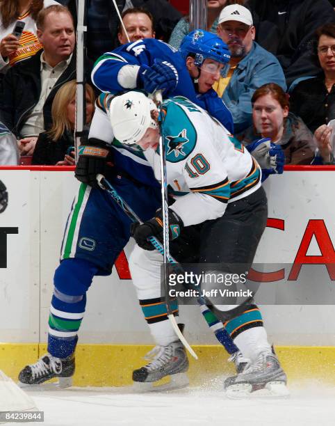 Christian Ehrhoff of the San Jose Sharks lays a hit along the boards on Alex Burrows of the Vancouver Canucks during their game at General Motors...