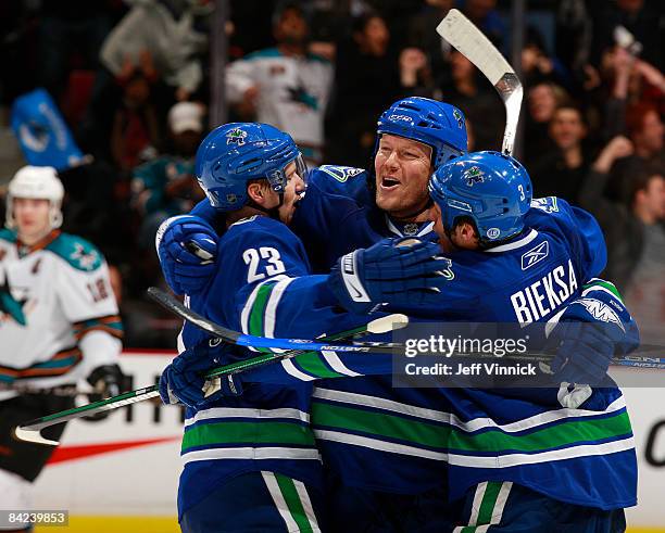 Mats Sundin of the Vancouver Canucks celebrates his first goal as a member of the Canucks with teammates Alex Edler and Kevin Bieksa during their...