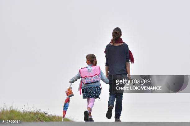 Girls walks to her primary school with her mother on the first day of the new school year in Vertou, western France, on September 4, 2017.