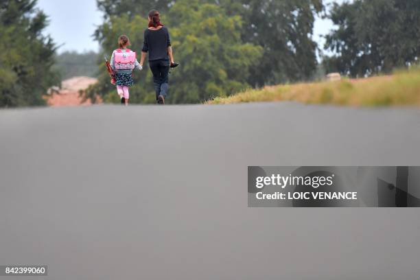 Girls walks to her primary school with her mother on the first day of the new school year in Vertou, western France, on September 4, 2017.