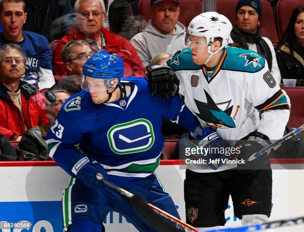 Joe Pavelski of the San Jose Sharks bodies Alexander Edler of the Vancouver Canucks along the boards during their game against the San Jose Sharks at...