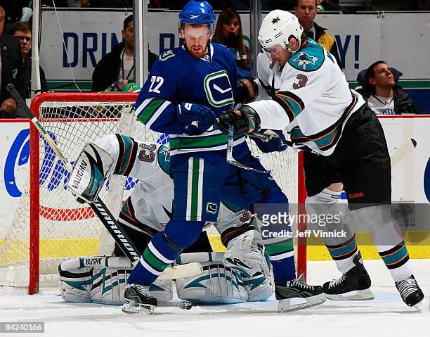 Douglas Murray of the San Jose Sharks bodies Daniel Sedin of the Vancouver Canucks while teammate Brian Boucher makes a save during their game at...