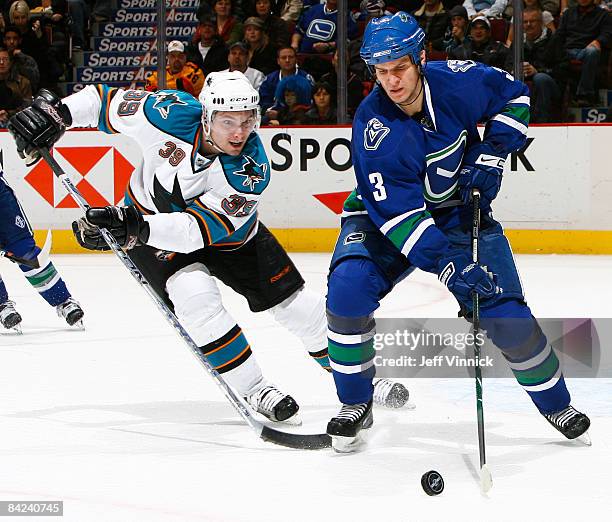Kevin Bieksa of the Vancouver Canucks and Tomas Plihal of the San Jose Sharks battle for the puck during their game at General Motors Place on...