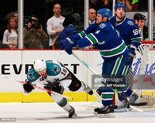 Willie Mitchell of the Vancouver Canucks checks Devin Setoguchi of the San Jose Sharks to the ice during their game at General Motors Place on...