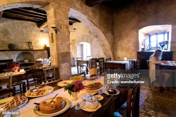 blond teenage girl eats breakfast in the ancient arched dining room in the diffused hotel of santo stefano di sextantio, in the medieval fortified village of santo stefano di sessanio; gran sasso national park; l'aquila province, abruzzo; italy; europe - abruzzo stock pictures, royalty-free photos & images