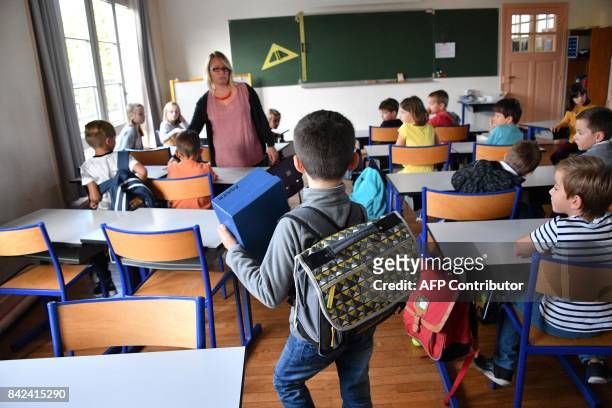 Pupils enter a classroom on the first day of school at the La Courbe primary school in Aytre, western France, on September 4, 2017. / AFP PHOTO /...