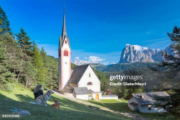 frauen genießen sie den blick mit ihren hunden, st. jacob kirche über val gardena dolomiten - sankt jakob stock-fotos und bilder