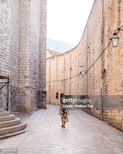 woman walking on st. dominic street in old town dubrovnik - ragusa stockfoto's en -beelden