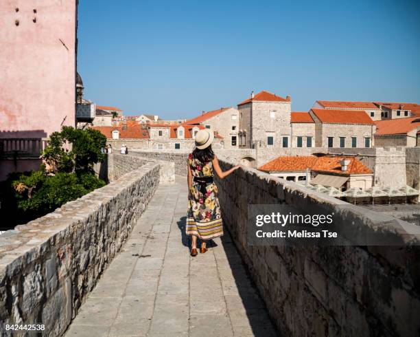 woman in hat walking along a section of the walls of dubrovnik - castle wall stock pictures, royalty-free photos & images