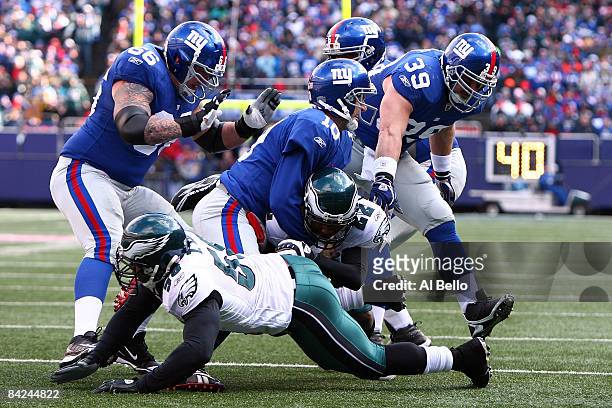 Asante Samuel of the Philadelphia Eagles is tackled by Eli Manning of the New York Giants after making an interception during the NFC Divisional...