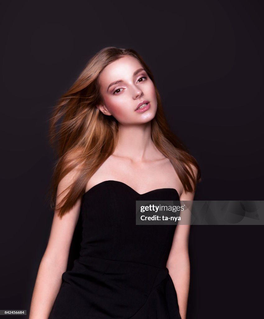 Beautiful young woman in luxury strapless dress on black background