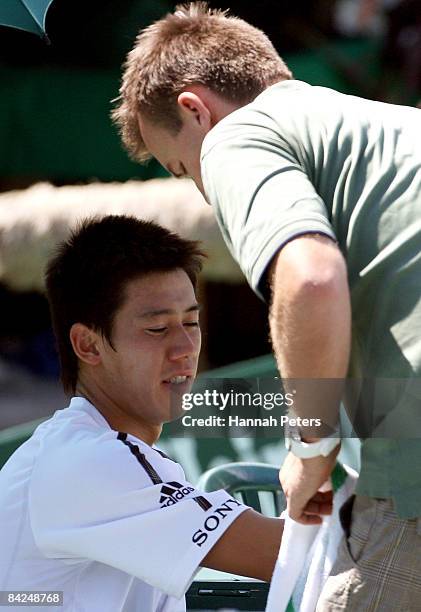 Kei Nishikori of Japan has his shoulder looked at during his first round match against Juan Carlos Ferrero of Spain during day one of the Heineken...