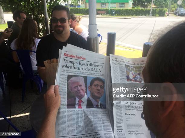 Tomas Pendola has a coffee in his favorite Cuban Café in Little Havana, while another customer reads a newspaper's article about the future of DACA....