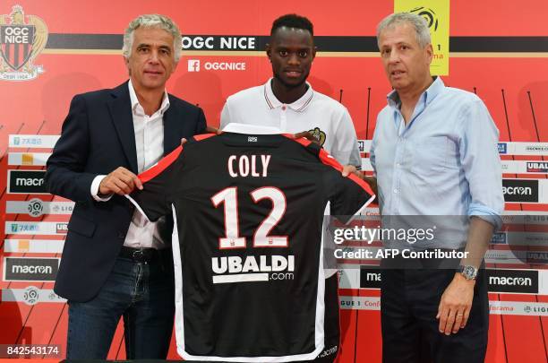 Nice football club's new recruit Senegalese defender Racine Coly poses with his new jersey between Swiss head coach Lucien Favre and French President...