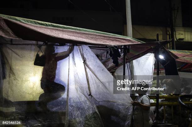 Vendors start to install transparent plastic to protect their merchandise as it starts to rain in Divisoria market in Manila on September 4, 2017. /...