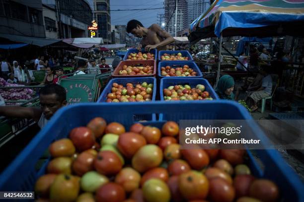 Worker arranges tomatoes on crates on a wooden cart in Divisoria market in Manila on September 4, 2017. / AFP PHOTO / NOEL CELIS