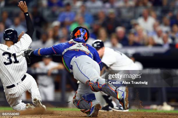 Rene Rivera of the New York Mets dives to tag Aaron Hicks of the New York Yankees during the game at Yankee Stadium on Monday, August 14, 2017 in the...