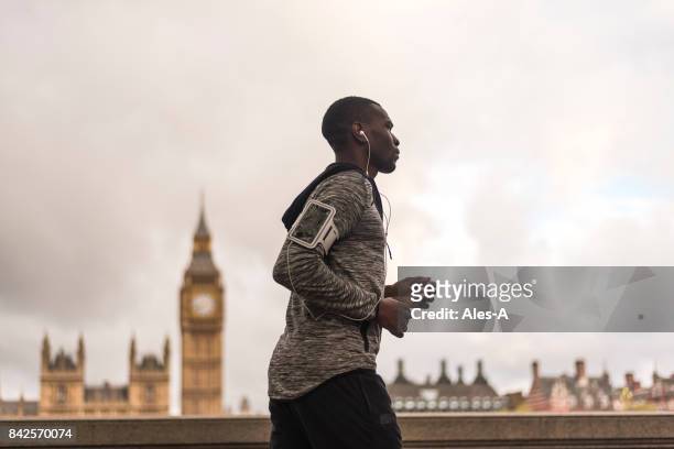 joven hombre negro corriendo al aire libre - man running city fotografías e imágenes de stock