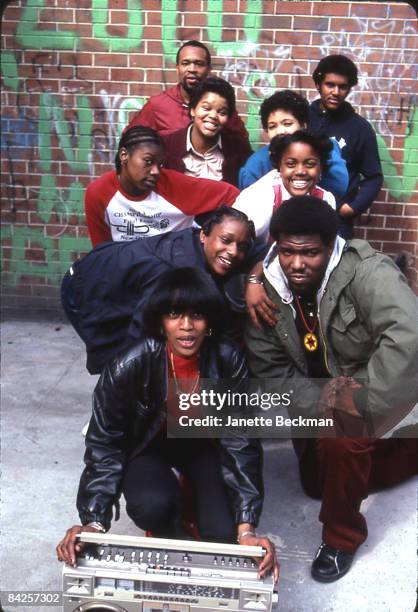 The 'Godfather of Hiphop' Afrika Bambaataa kneeling for a portrait with a group of friends in the Bronx, 1983. A woman at the front of the group...