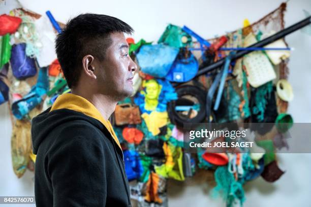 Chinese artist Liu Bolin poses in front of his artwork during the preview of his exhibition at the Beijing Paris gallery on September 4, 2017 in...