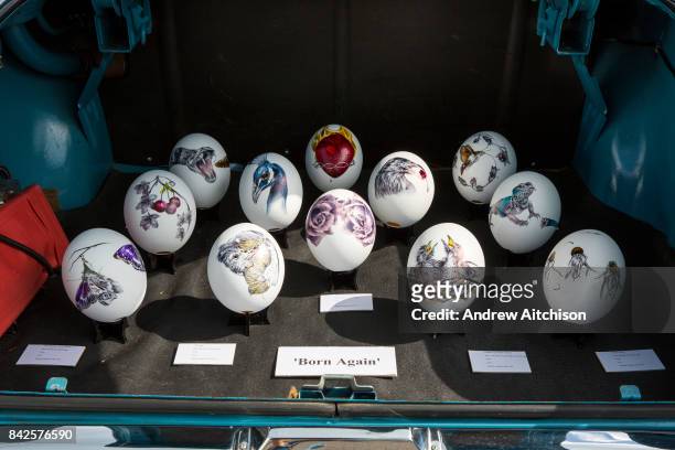 Painted ostrich eggs in the boot of a Vauxhall car by artist Kate Knight on sale at the 2017 Art Car Boot Fair, Folkestone, Kent.
