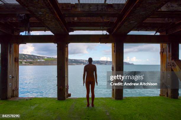 An Antony Gormley cast iron figure from the series Another Time located on the half tide loading bay of the Folkestone Harbour Arm. Part of the 2017...