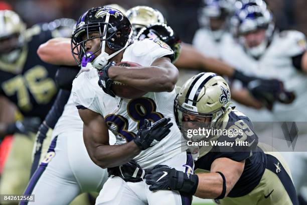 Bobby Rainey of the Baltimore Ravens runs the ball and is tackled by Adam Bighill of the New Orleans Saints during a preseason game at Mercedes-Benz...