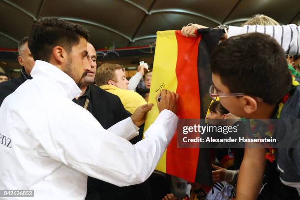 Sami Khedira of Germany signed a German flag of fans after the FIFA 2018 World Cup Qualifier between Germany and Norway at Mercedes-Benz Arena on...