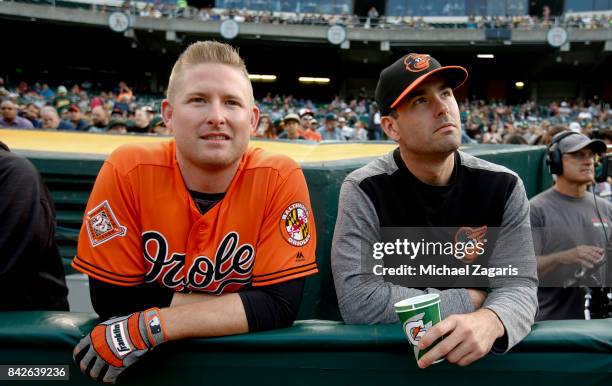 Mark Trumbo and Seth Smith of the Baltimore Orioless stand in the dugout prior to the game against the Oakland Athletics at the Oakland Alameda...