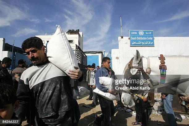Palestinians are seen carrying food aid from the United Nations Relief and Works Agency in al-Shati refugee camp on January 13 in Gaza City, Gaza...