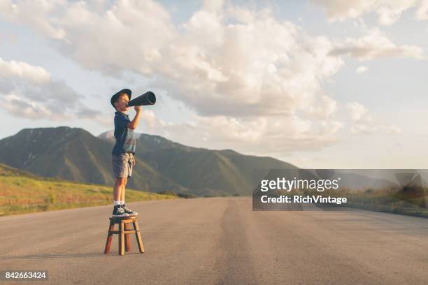 young boy speaks through megaphone - persuasion imagens e fotografias de stock