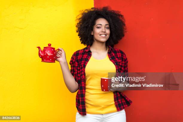 lächelnde hausfrau mit roten teekanne und tasse - multi coloured shirt stock-fotos und bilder