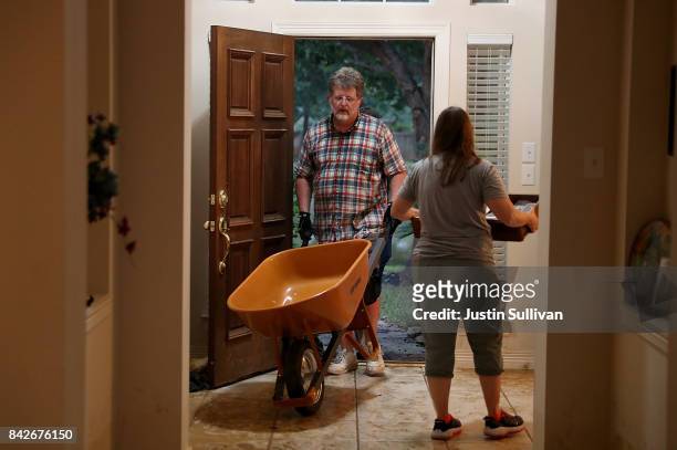 Mark Teague pushes a wheelbarrow past his wife Melissa Teague as they clean out their flooded home on September 4, 2017 in Katy, Texas. Over a week...